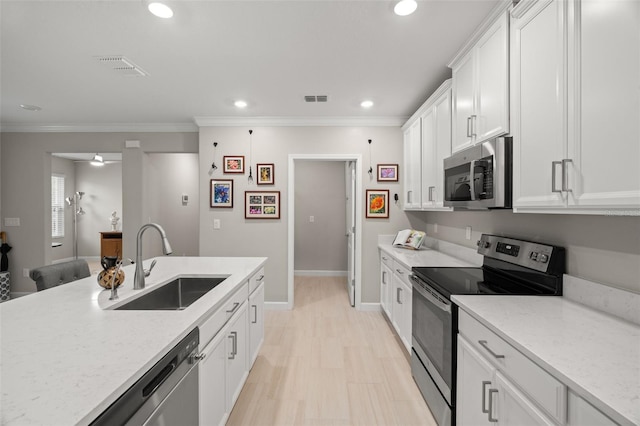 kitchen with appliances with stainless steel finishes, white cabinetry, sink, and ornamental molding