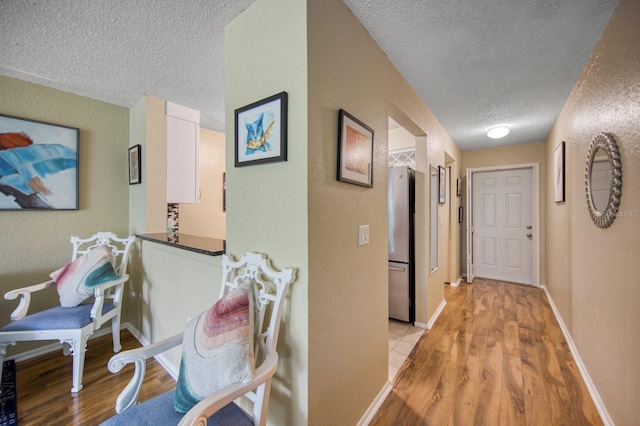 hallway featuring a textured ceiling and light wood-type flooring