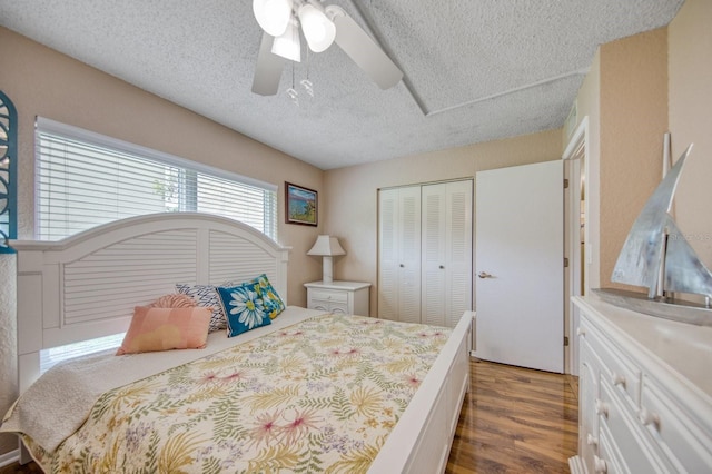 bedroom featuring dark wood-type flooring, a closet, ceiling fan, and a textured ceiling