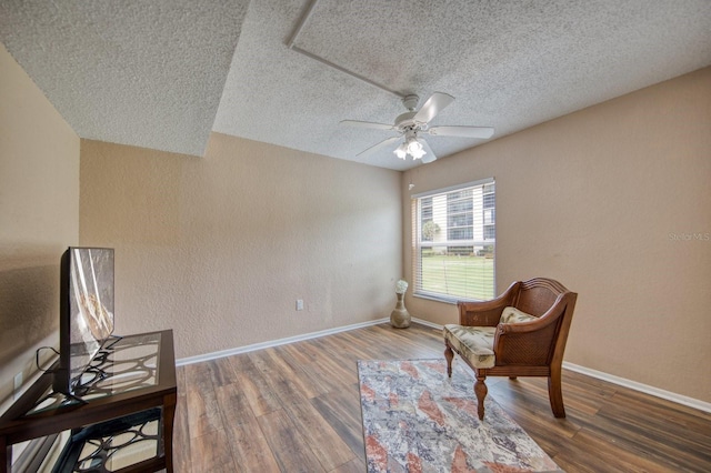 sitting room with a textured ceiling, wood-type flooring, and ceiling fan