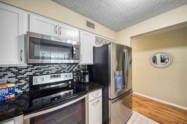 kitchen featuring white cabinets, backsplash, light hardwood / wood-style flooring, and stainless steel appliances