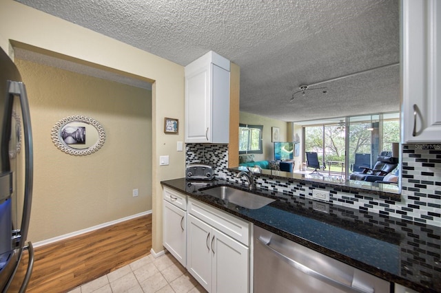 kitchen with sink, white cabinets, backsplash, and appliances with stainless steel finishes