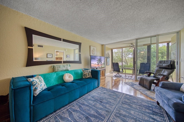 living room featuring a healthy amount of sunlight, a textured ceiling, floor to ceiling windows, and hardwood / wood-style floors