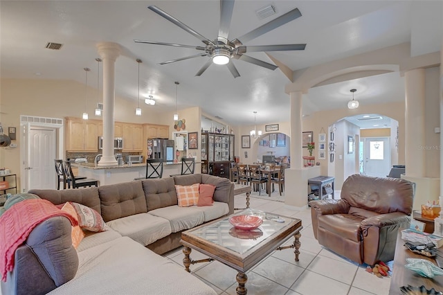 living room featuring decorative columns, light tile flooring, ceiling fan, and vaulted ceiling