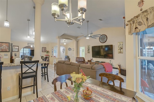 tiled dining room with plenty of natural light, ceiling fan with notable chandelier, and high vaulted ceiling