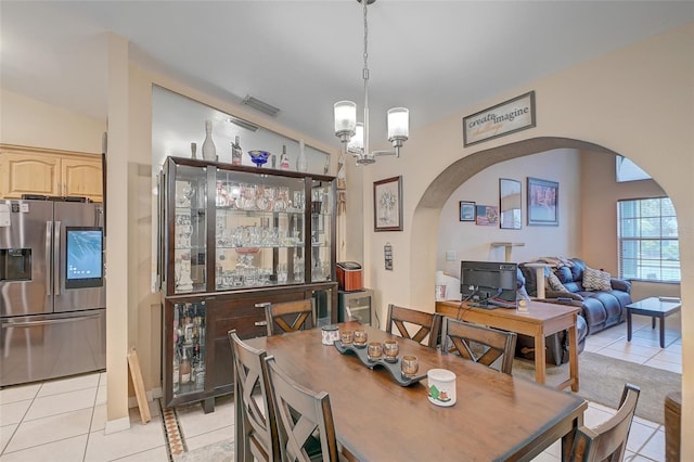 tiled dining space featuring an inviting chandelier and vaulted ceiling