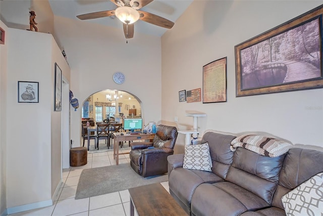 tiled living room featuring high vaulted ceiling and ceiling fan with notable chandelier