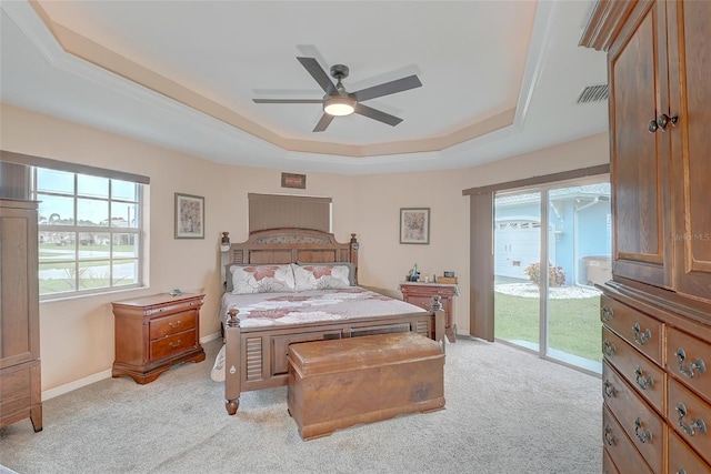 bedroom featuring ceiling fan, access to exterior, a tray ceiling, and light carpet