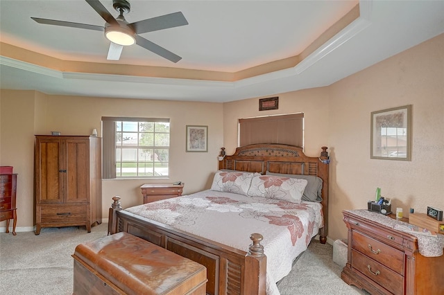 carpeted bedroom featuring ceiling fan and a raised ceiling