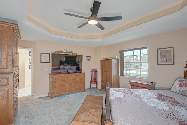 bedroom with ceiling fan, a tray ceiling, and light colored carpet