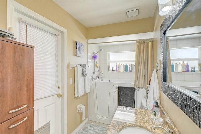 bathroom with a wealth of natural light, a relaxing tiled bath, and tile floors