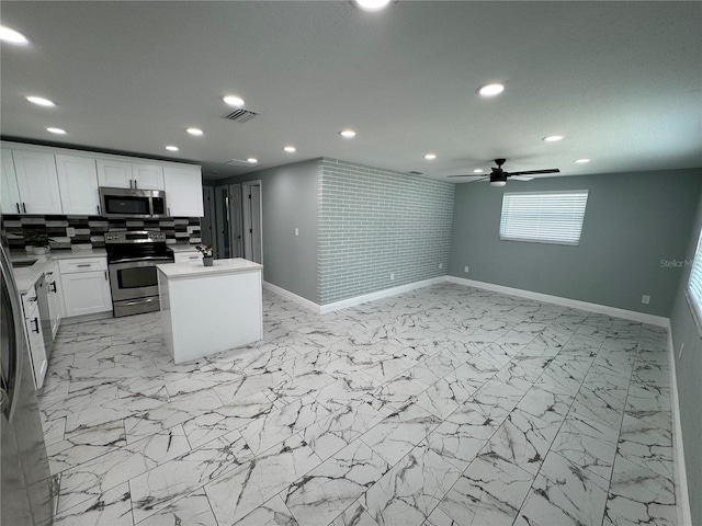 kitchen with white cabinetry, stainless steel appliances, backsplash, light tile flooring, and ceiling fan