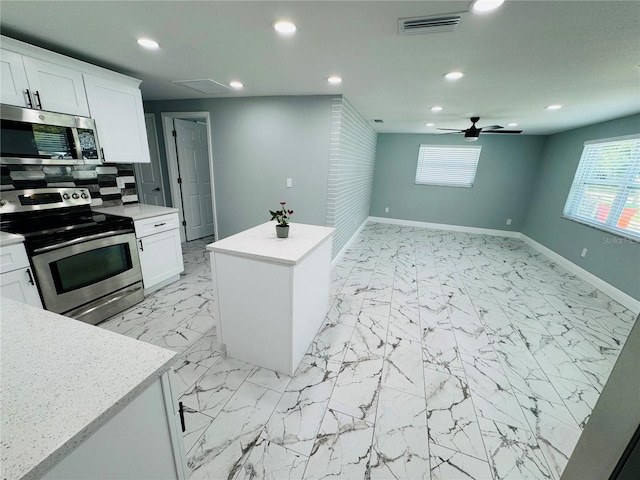 kitchen featuring a kitchen island, stainless steel appliances, white cabinets, tasteful backsplash, and ceiling fan