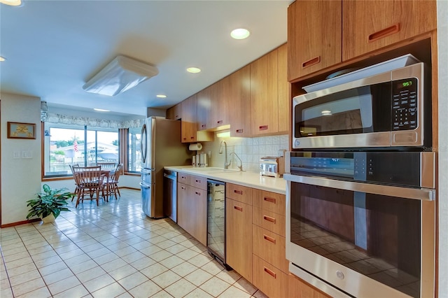 kitchen featuring backsplash, sink, light tile patterned floors, and stainless steel appliances