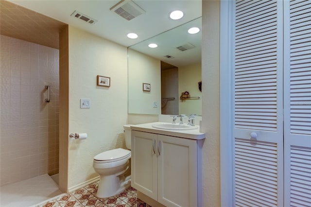 bathroom with tile patterned floors, vanity, a tile shower, and toilet