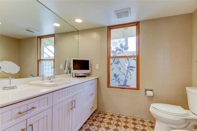 bathroom with tile patterned flooring, vanity, toilet, and tile walls