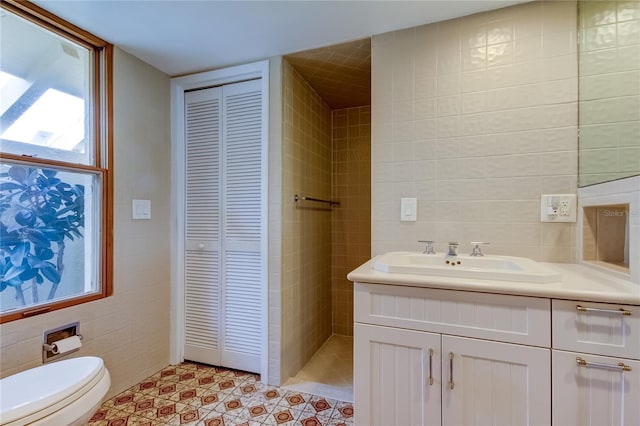 bathroom featuring tile patterned flooring, vanity, tile walls, and toilet