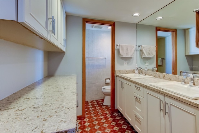 bathroom featuring vanity, toilet, and tile walls