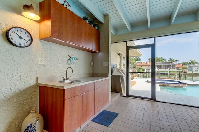 kitchen with beam ceiling, light tile patterned floors, wood ceiling, and sink