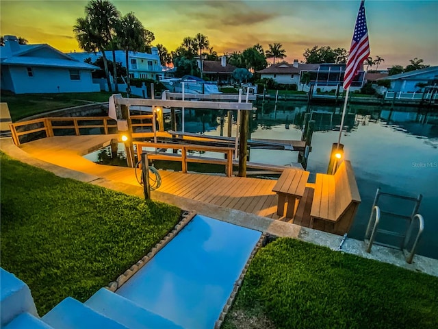 view of dock featuring a lawn and a water view