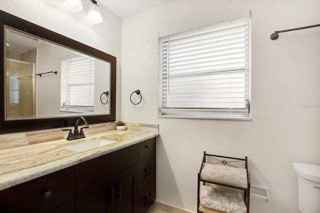 bathroom with toilet, a shower, and vanity