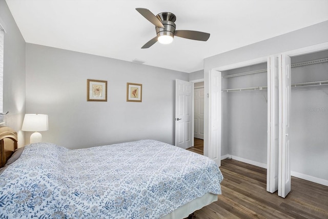 bedroom with ceiling fan, dark hardwood / wood-style flooring, and multiple closets