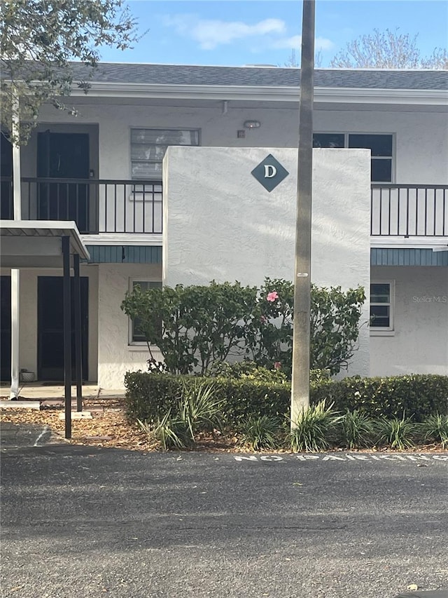 view of side of property with stucco siding and a shingled roof