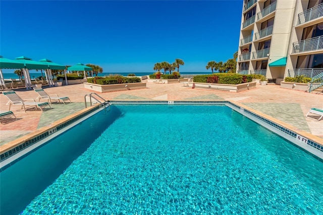 view of pool featuring a patio and a water view