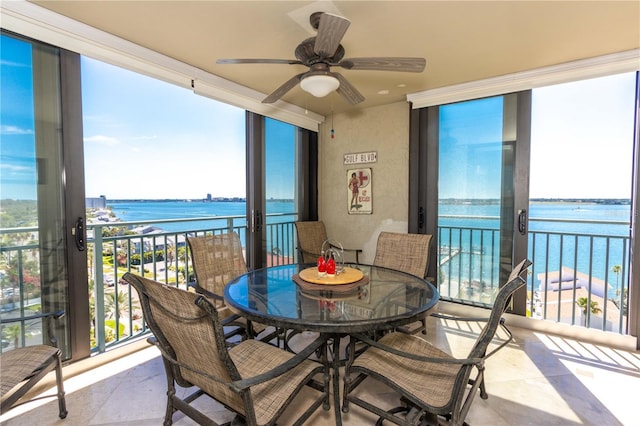 sunroom with ceiling fan and a water view