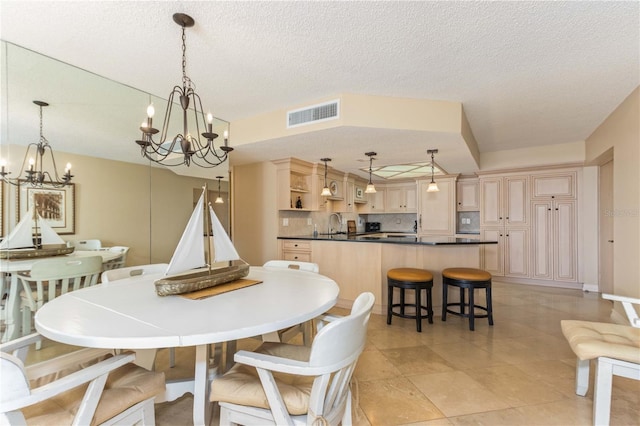 dining room featuring sink, a textured ceiling, and a chandelier