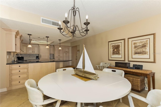 tiled dining area with a textured ceiling, an inviting chandelier, and sink