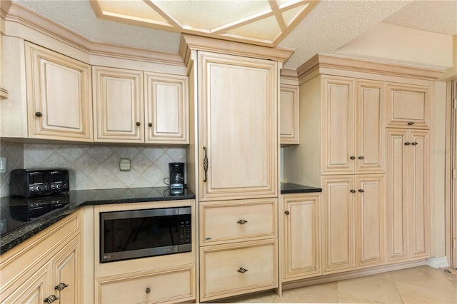 kitchen featuring cream cabinetry, light tile patterned floors, backsplash, and stainless steel microwave