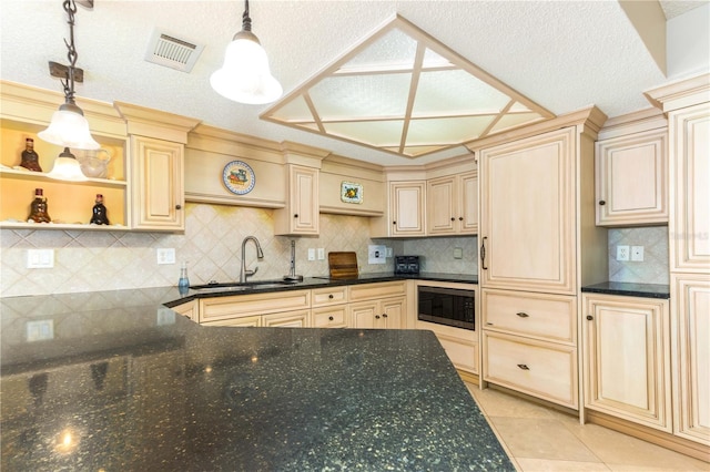 kitchen with tasteful backsplash, built in microwave, sink, light tile patterned floors, and decorative light fixtures