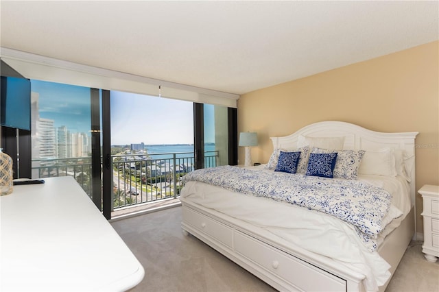 carpeted bedroom featuring access to exterior, a water view, and floor to ceiling windows