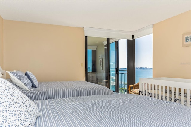 bedroom with access to outside, a water view, and a wall of windows