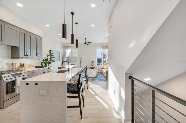 kitchen with gray cabinetry, ceiling fan, sink, pendant lighting, and stainless steel range with gas cooktop