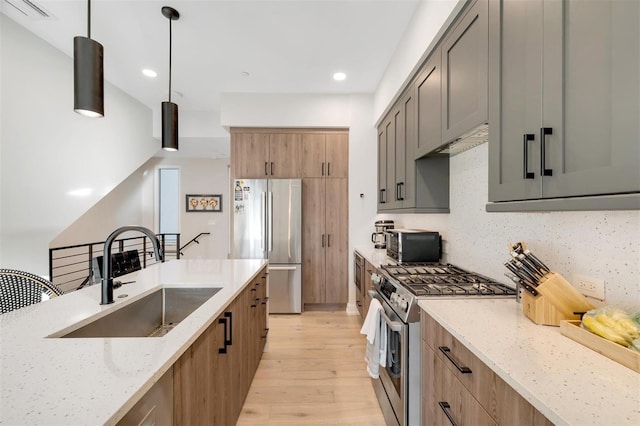 kitchen with light stone countertops, sink, tasteful backsplash, decorative light fixtures, and appliances with stainless steel finishes