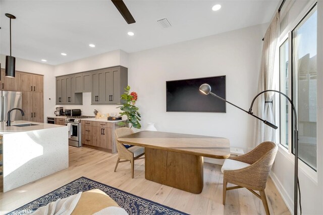 dining room with sink, a healthy amount of sunlight, and light wood-type flooring