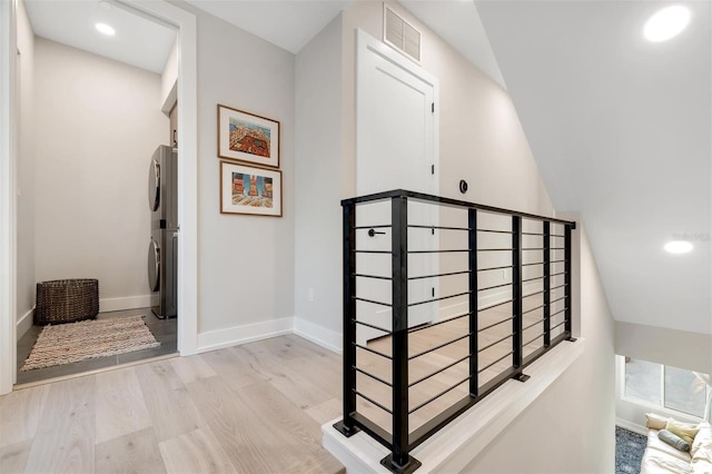 staircase with hardwood / wood-style floors and stacked washer and clothes dryer