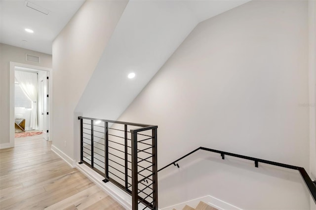 staircase with hardwood / wood-style floors and lofted ceiling