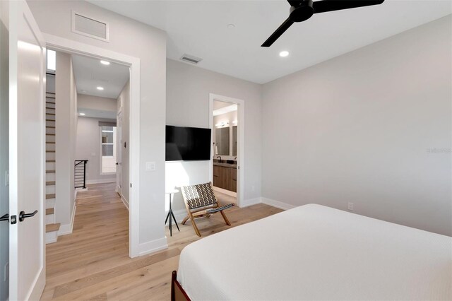 bedroom featuring ceiling fan, light hardwood / wood-style floors, and ensuite bathroom