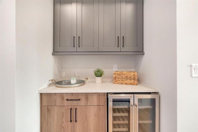 bar with wine cooler and light stone countertops