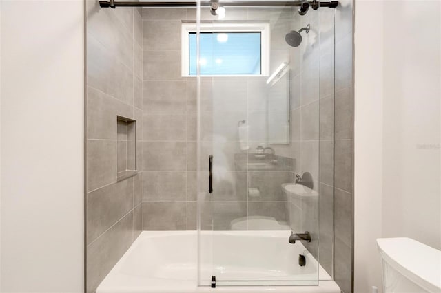 bathroom with toilet and bath / shower combo with glass door