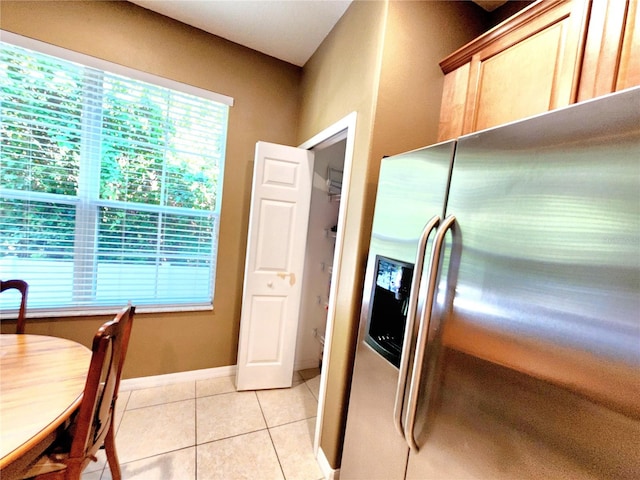 kitchen featuring stainless steel fridge, light tile patterned floors, and light brown cabinetry