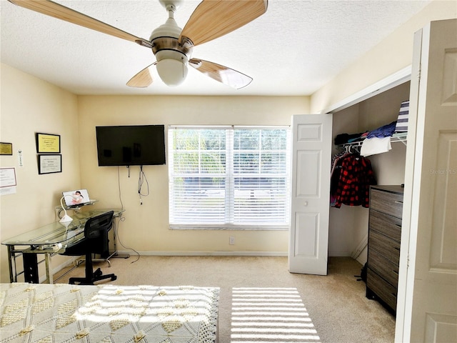 bedroom with ceiling fan, a closet, light colored carpet, and a textured ceiling