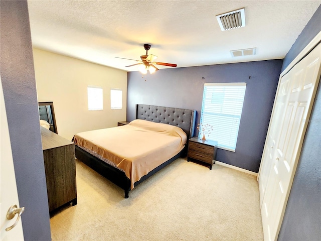 bedroom with ceiling fan, a closet, and light colored carpet