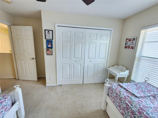 bedroom featuring light colored carpet, a closet, and ceiling fan