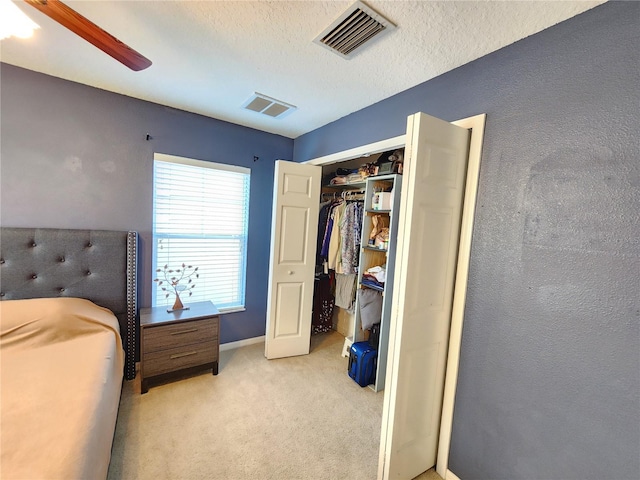 carpeted bedroom featuring ceiling fan, a closet, and a textured ceiling