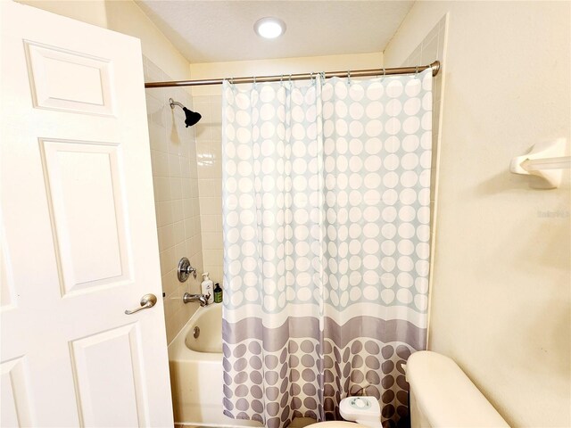 bathroom featuring shower / bath combination with curtain and toilet