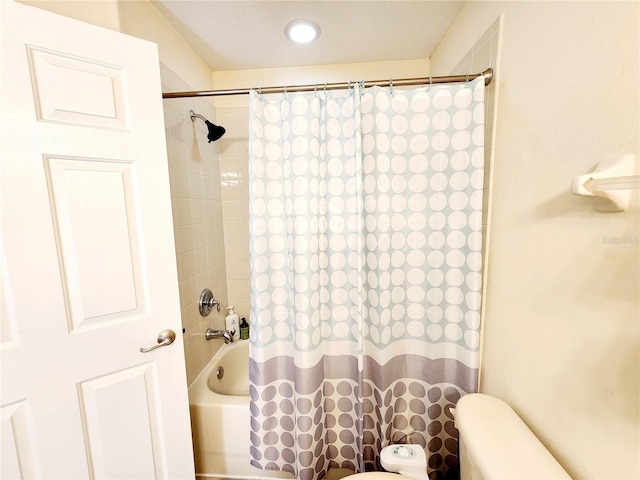 bathroom featuring shower / bathtub combination with curtain and toilet